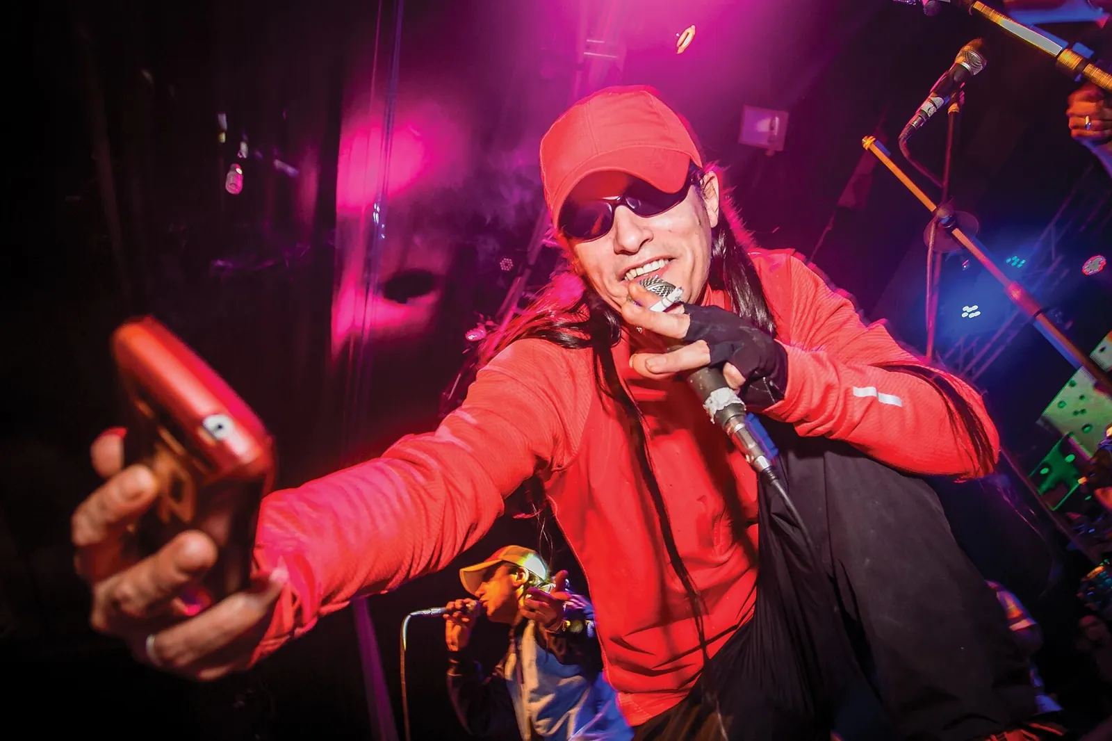 Hernán Coronel canta en vivo con campera roja bajo luces de colores