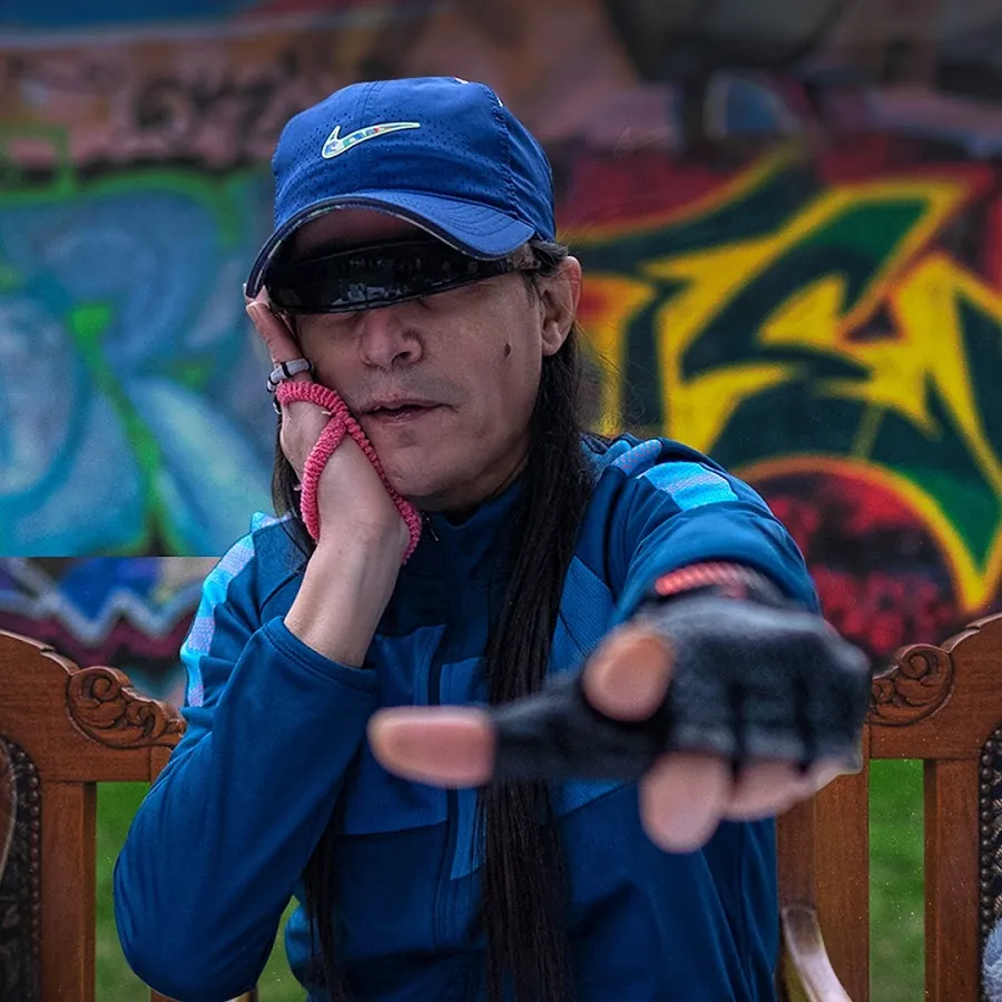 Retrato de Hernán Coronel con gorra azul frente a un grafiti